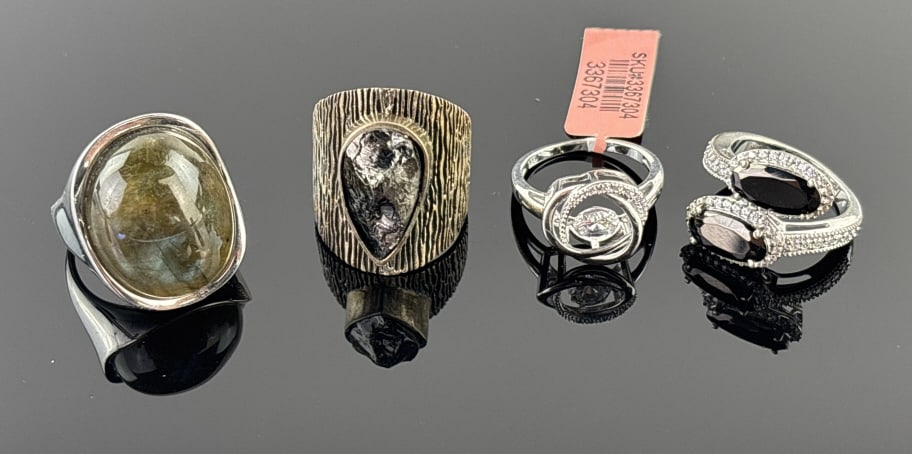 (4) 925 Sterling Silver Rings with Gemstones. Total Weight: 31.72 grams: (4) 925 sterling silver rings featuring gemstones in sizes 9 and 7. One ring features a black teardrop-shaped stone, the second features a hanging circle-cut clear stone with clear stone accents and i