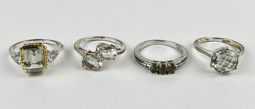 (4) 925 Sterling Silver Rings featuring Green Gemstones. Total Weight: 10.21 grams: (4) 925 sterling silver rings featuring green gemstones. Size 7. The first ring features a rectangle-cut light green gemstone with blue gemstone accents. The second ring features a circle-cut light gr