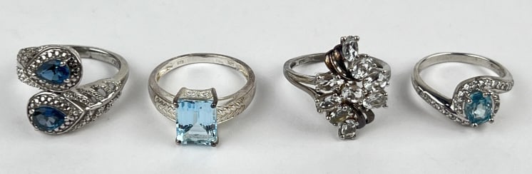 (4) 925 Sterling Silver Rings with Gemstones: TW: 16.15 grams. (4) 925 sterling silver rings featuring blue gemstones. Size 7, 8, and 9. The first ring features an oval-cut blue gemstone with clear gemstone accents. The second ring features a rec