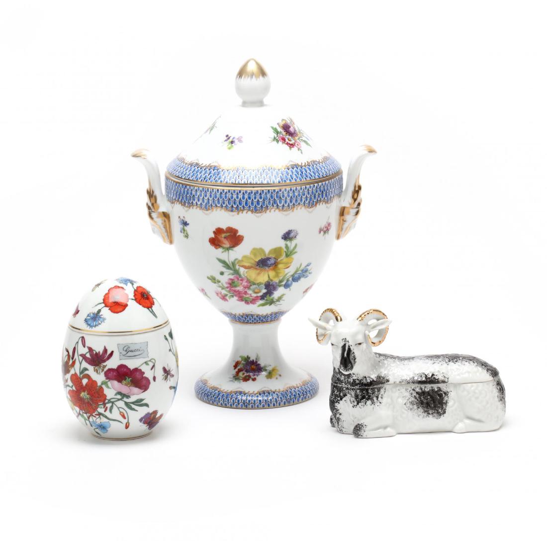 Group of Three Porcelain Boxes: 20th century, to include a figure of a recumbent ram; a lidded egg box with floral motif (marked Bernardaud Limoges France to underside, Gucci decoration to body of egg); and a tall double handled lid