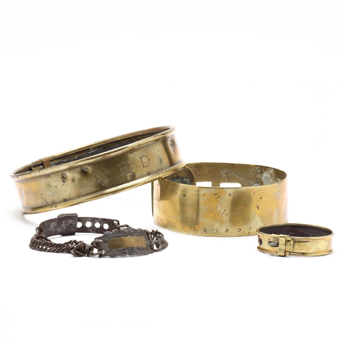 Four Antique Brass Dog Collars: 19th century, the largest engraved "NED" the second with illegible engraving, and one steel and brass chain collar reading "Breck Hugh Mitchell, Port Tobacco, Md." Largest 8 in. diameter. Estate of th