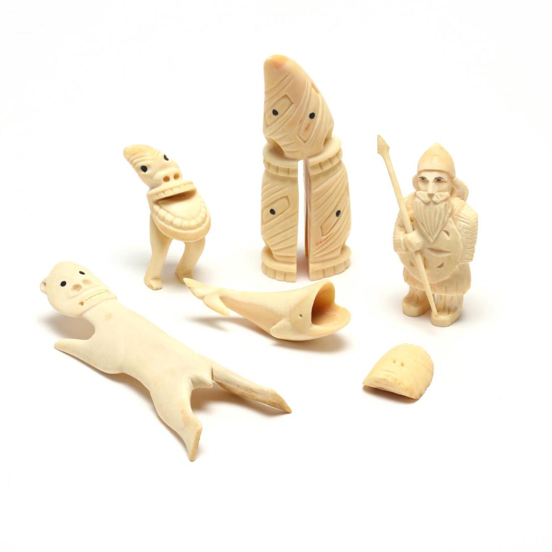 Greenland Inuit Carving Group: carved whale's teeth including a figure of a hunter with spear, a totem, whale, mask, Tupilak figure and a polar bear, inlaid ebony eyes. Tallest 5.25 in. The Native American Collection of Mr. Wayne L