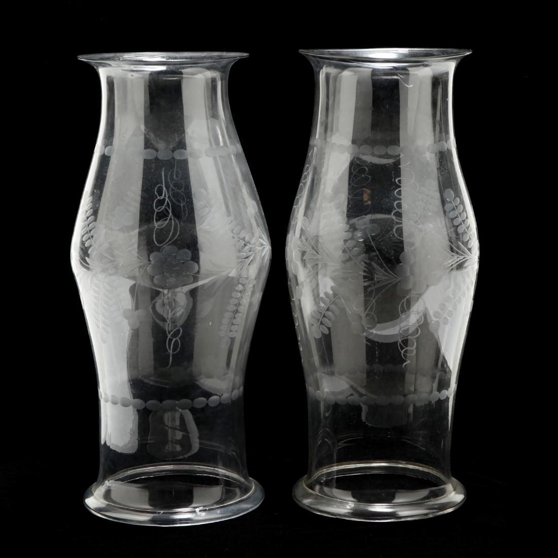 Pair of Large Engraved Glass Hurricane Shades: mid to late 20th century, blown glass with engraved grape vine decoration, curled and polished foot. 23 x 9 in. diameter. From The Collection of the Late Stuart Walston and Doris Schaum Walston of Wil