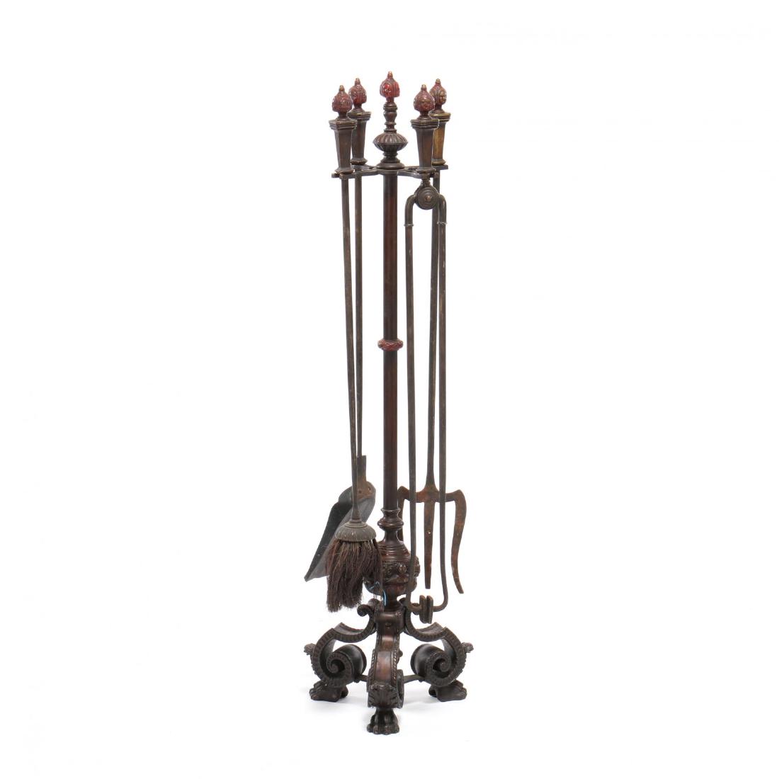 Spanish Renaissance Revival Cast Bronze Fireplace Tool: late 19th century, red enamel decoration, each with mask form finials, the stand with scrolled base and paw feet, including broom, shovel, tongs and fork. 44 in. From the Collection of a Gentleman, Fl