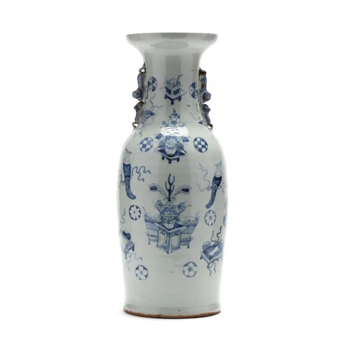A Large Chinese Blue and White Vase: 19th century, porcelain hand painted in underglaze blue with Buddhist motifs and vases filled with flora and fauna, faux animal handles on the vase's neck, open wide rim. 23.5 in. The Gills-Peple Coll