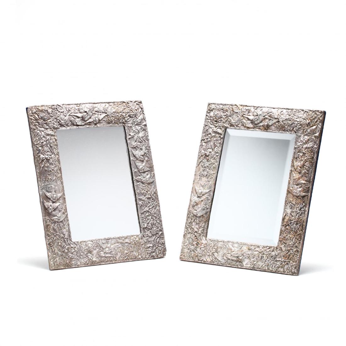 A Pair of Sterling Silver Dressing Table Mirrors: 20th century, both profusely decorated in the Aesthetic style with swallows and dragon flies amidst flowers against a stippled ground, rectangular form with easel backs, marked "JR" and "925." DOA 19.