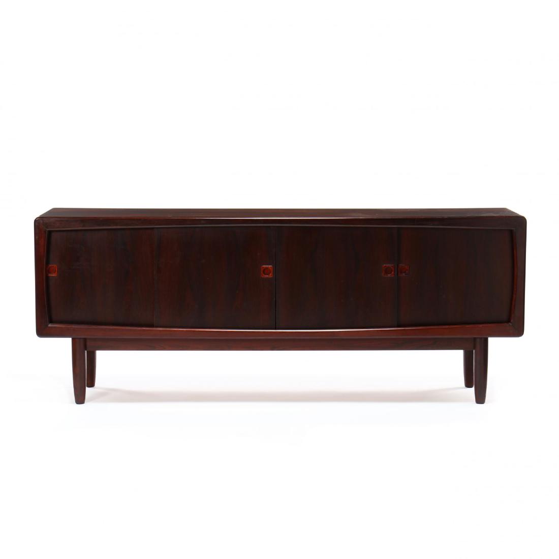 Danish Rosewood Sideboard: 1960s, likely by Falster MÃ¸belfabrik, case with rounded edges, four sliding doors with three central felt lined drawers flanked by shelved compartments, raised on turned and tapered legs, back righ