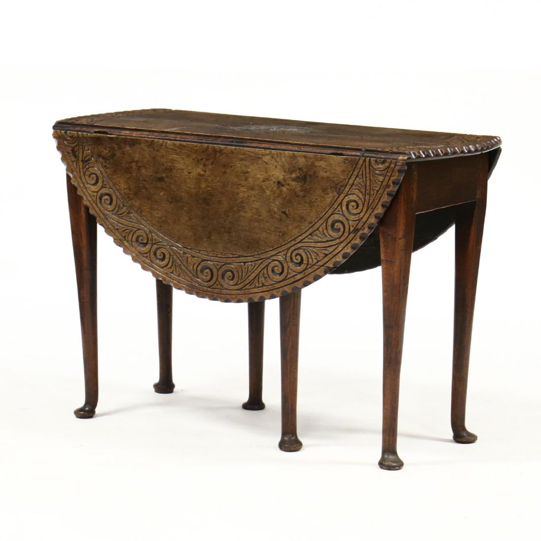 English Transitional Oak Drop Leaf Breakfast Table: English Transitional Oak Drop Leaf Breakfast Table 18th century, relief carved oval top featuring geometric and scrolled design with chip carved edge demilune drop leaves with gateleg support, raised 