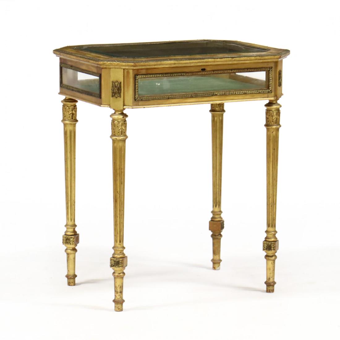 Louis XVI Style Gilt and Ormolu Mounted Vitrine Table: Louis XVI Style Gilt and Ormolu Mounted Vitrine Table circa 1900, mahogany with all over gilt surface, case with canted corners and beveled glass hinged lid, green velvet lined interior raised on tape
