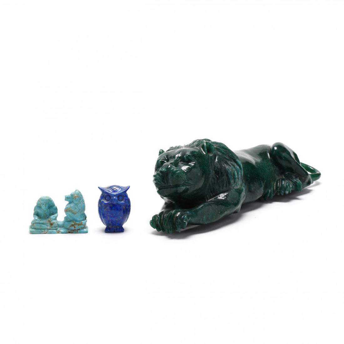 Three Carved Hardstone Animals: Three Carved Hardstone Animals 20th century, including a green stone recumbent lion, lapis owl, and an Egyptian style carved turquoise seated figure with monkey. Lion 3 x 11 x 4 in. The Estate of the 