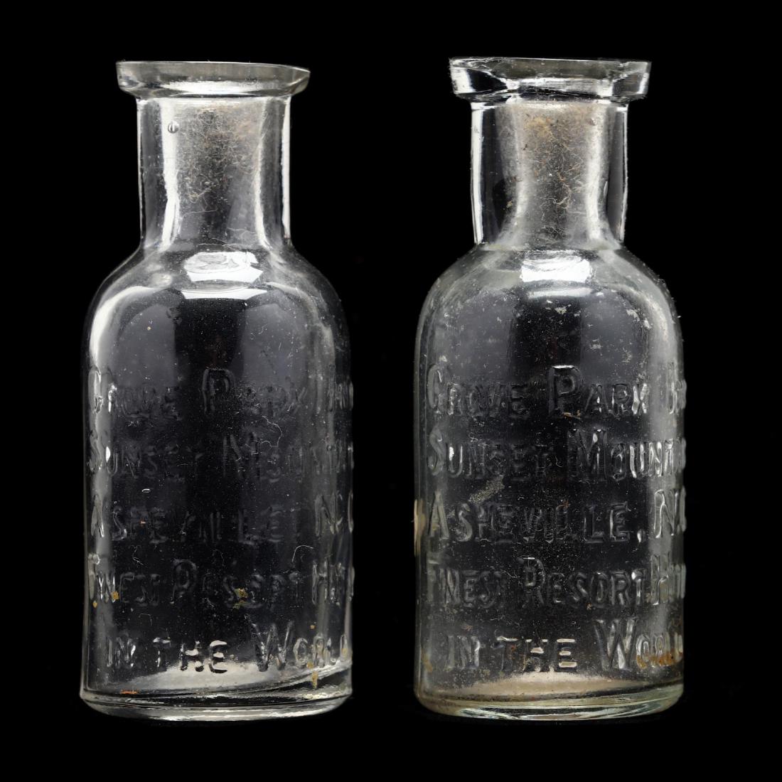 Pair of Small Grove Park Inn Advertising Bottles: Pair of Small Grove Park Inn Advertising Bottles circa 1900, pressed clear glass with raised lettering reading "Grove Park Inn, Sunset Mountain, Asheville, NC, Finest Resort Hotel, In The World." 2.5 