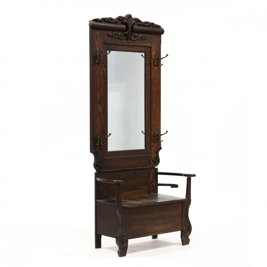 Antique American Carved Oak Hall Tree: Antique American Carved Oak Hall Tree late 19th century, one part form, four brass coat hooks surrounding a rectangular mirror, lift lid seat and metal cane hook. 83 x 38 x 18 in. Additional high-reso