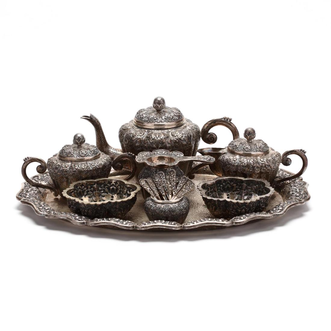 An Indonesian Yogya Silver Tea Service: An Indonesian Yogya Silver Tea Service mid-20th century, (20) pieces including an oval tray (18.5 x 14.5 in.), teapot, sugar bowl with cover, creamer with cover, tea strainer with stand, (2) waste bow