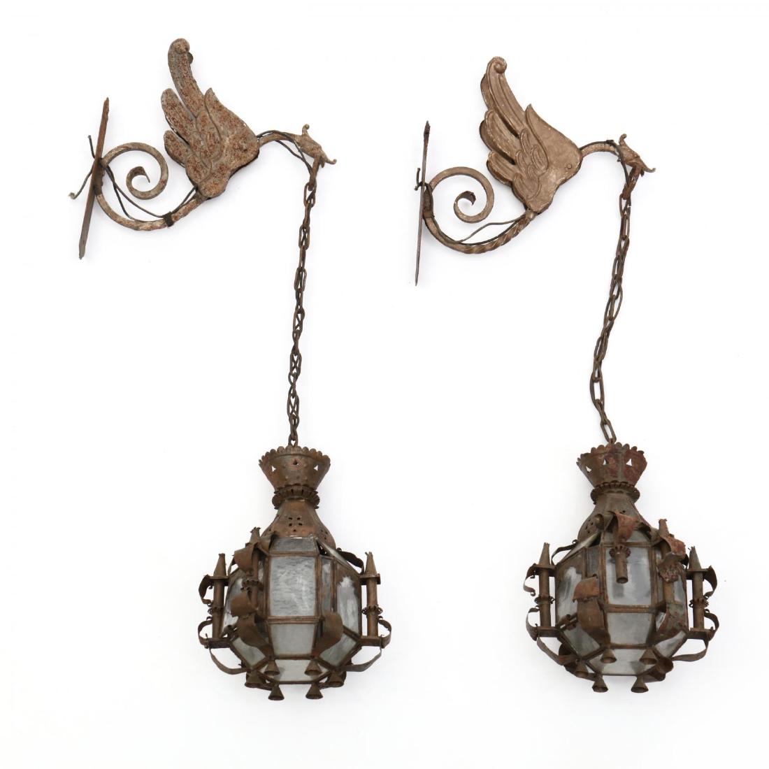 Pair of Moroccan Hanging Wall Lanterns: Pair of Moroccan Hanging Wall Lanternsearly 20th century, winged griffin scrolled wall mount, supporting a lantern with cut metal design and glass windows, single hinged door for entry. 32 x 9 x 12 in