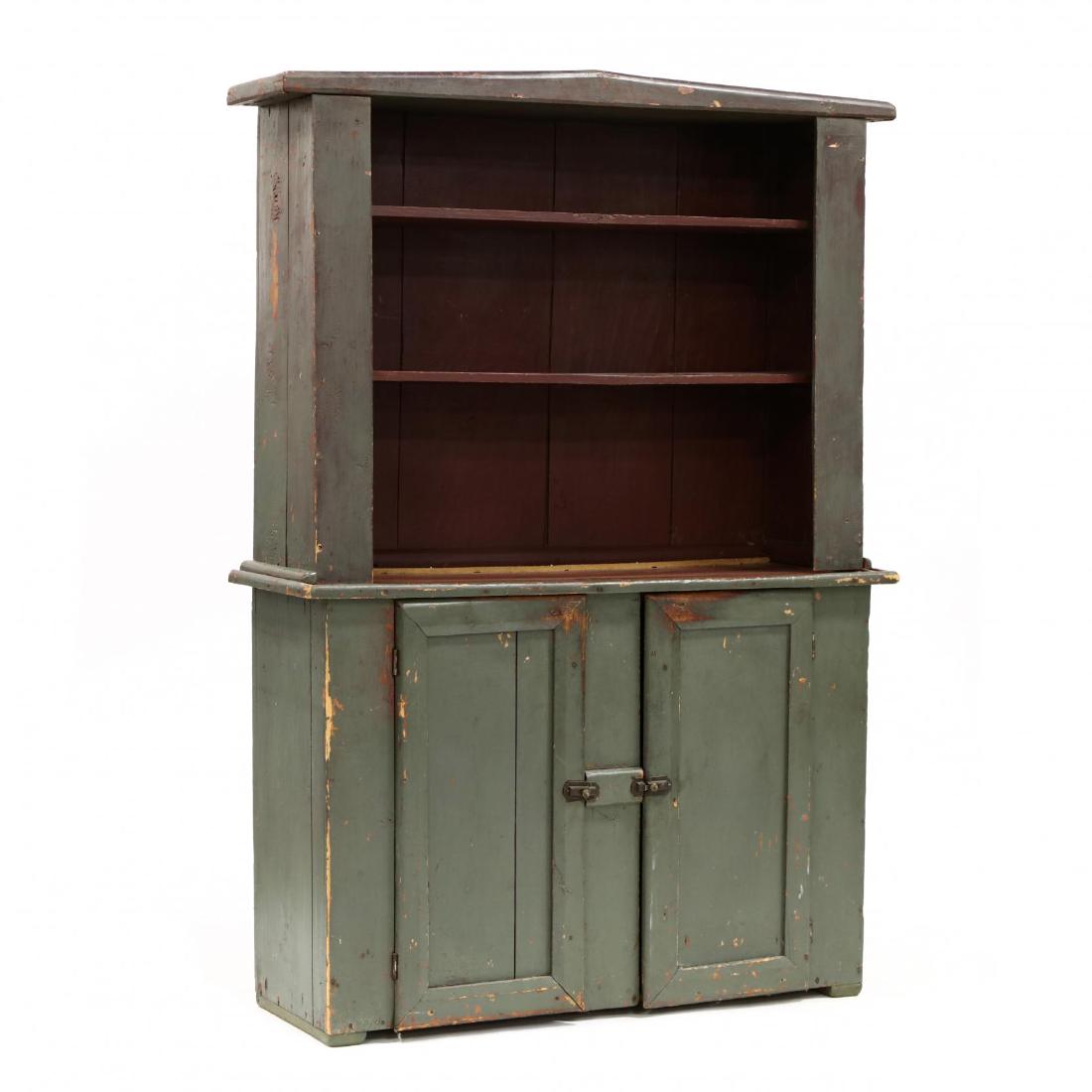 Antique American Painted Step Back Cupboard: Antique American Painted Step Back Cupboard19th century, two part form, later green and red paint, upper open cabinet with fixed dish shelves, lower cabinet with two hinged recessed panel doors having