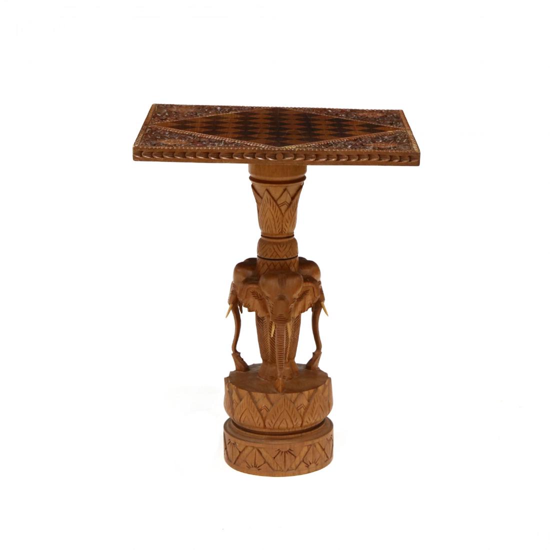 African, Carved and Inlaid Games Table: African, Carved and Inlaid Games Table mid 20th century, checkerboard inlaid top with relief carved corners, pedestal base featuring three carved elephants. 24 x 18.5 x 19 in. Additional high-resoluti