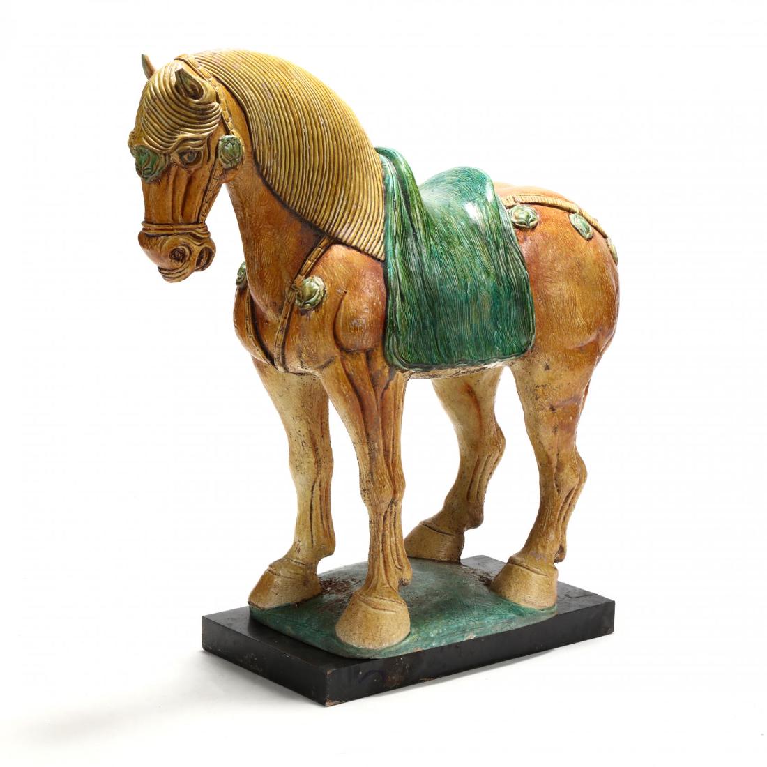 A Large Tang Style Horse: A Large Tang Style Horse mid 20th century, sancai glazed terra cotta, the horse crafted on a terra cotta base glazed green mounted onto an ebonized wood plinth. Horse 33 x 11 x 34 in. From the Estate 