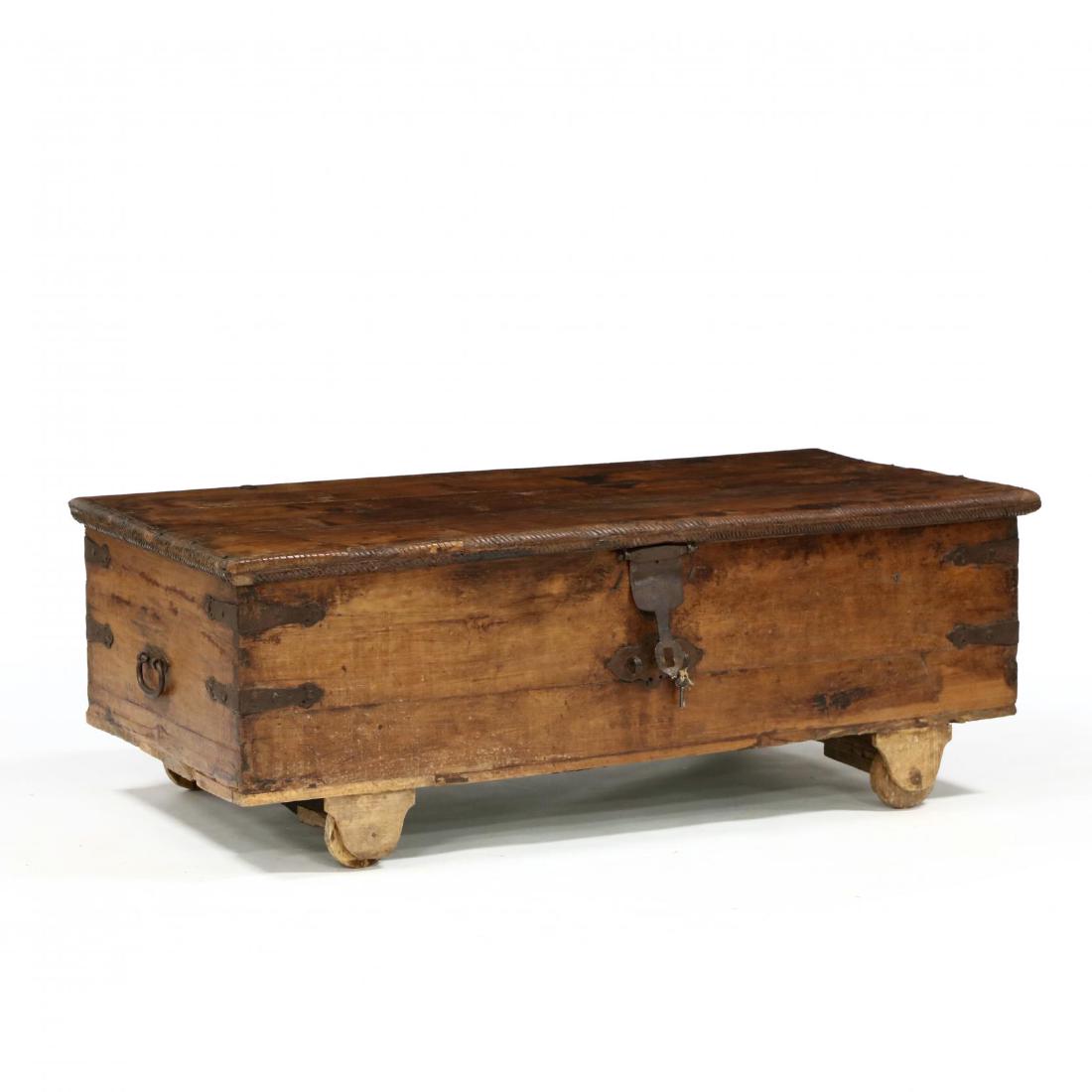 Southeast Asian Large Carved Wood Chest: Southeast Asian Large Carved Wood Chest19th century, appears to be teak, hinged lid with carved edge, open interior, dovetailed case with iron straps and bail handles, raised on later wood wheels. 22