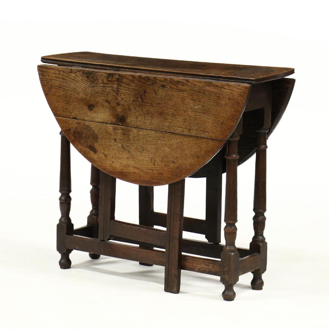 William and Mary Oak Drop Leaf Table: William and Mary Oak Drop Leaf Table circa 1700, top with rounded edge, raised on straight molded gate legs, with ring and baluster turned outer legs, on onion feet. 27.5 x 11 x 32 in. Each leaf 14 in