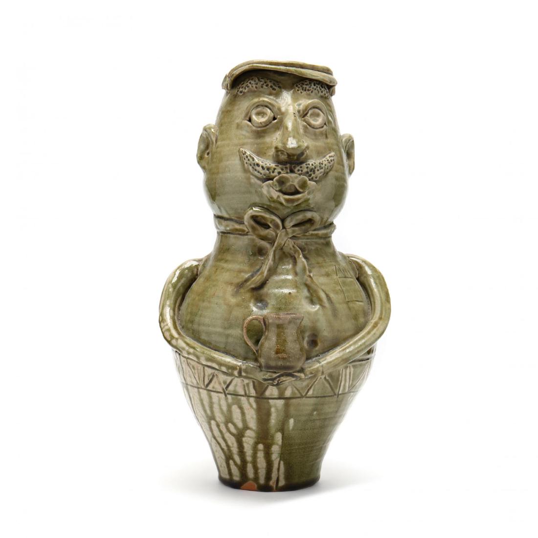 NC Folk Art Potter, Vicki Miller Ram Pottery: NC Folk Art Potter, Vicki Miller Ram Pottery green glazed earthenware figure of a man holding a pitcher, signed on the bottom. 13.5 in. From the Collection of Mary Wells, Greensboro, North Carolina