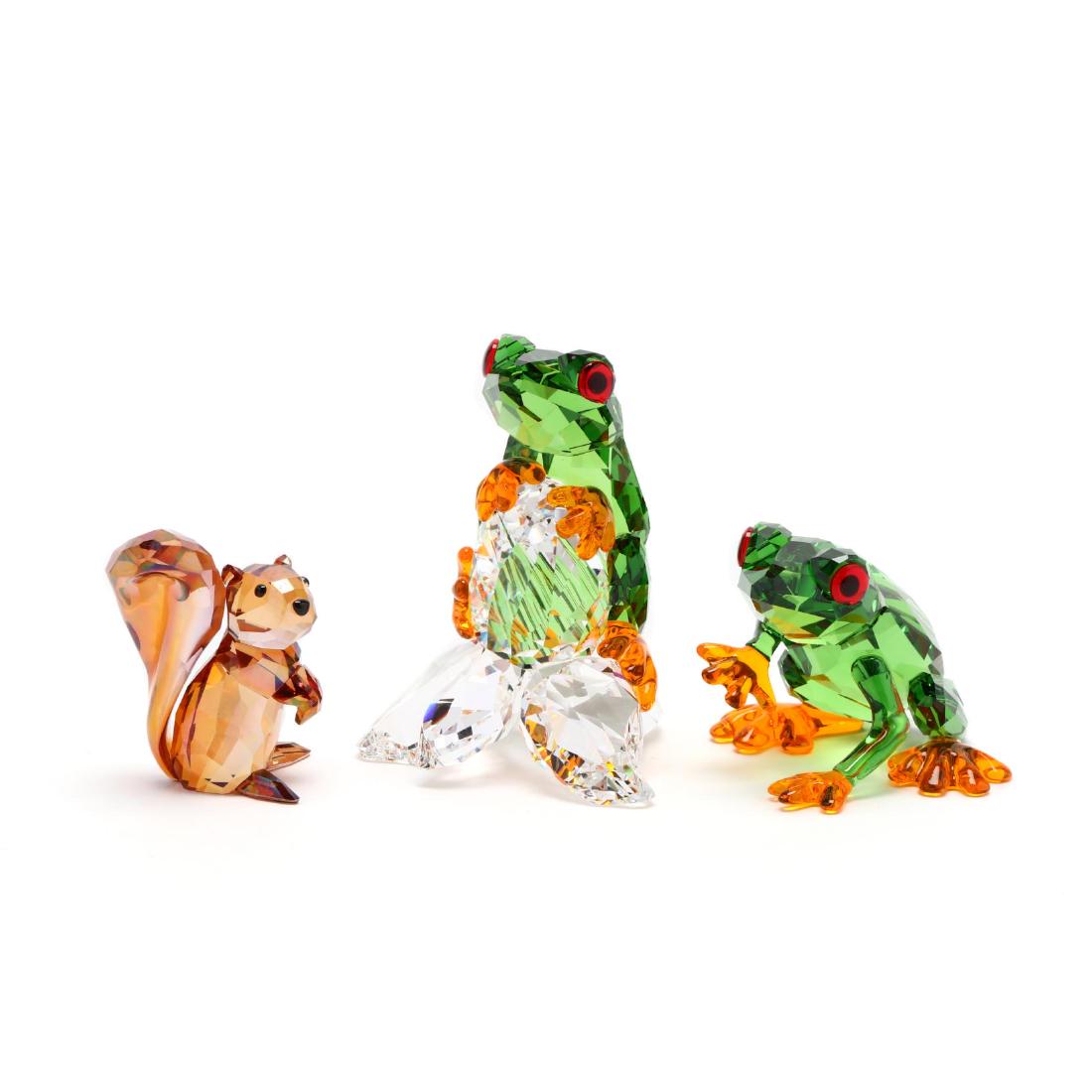 Swarovski, Three Woodland Animals: Swarovski, Three Woodland Animals including Frogs #5136807 in green/red/orange/clear crystal with one frog on a flower and the other in motion (taller 3 in.); and Squirrel #1142807 in iridescent brown