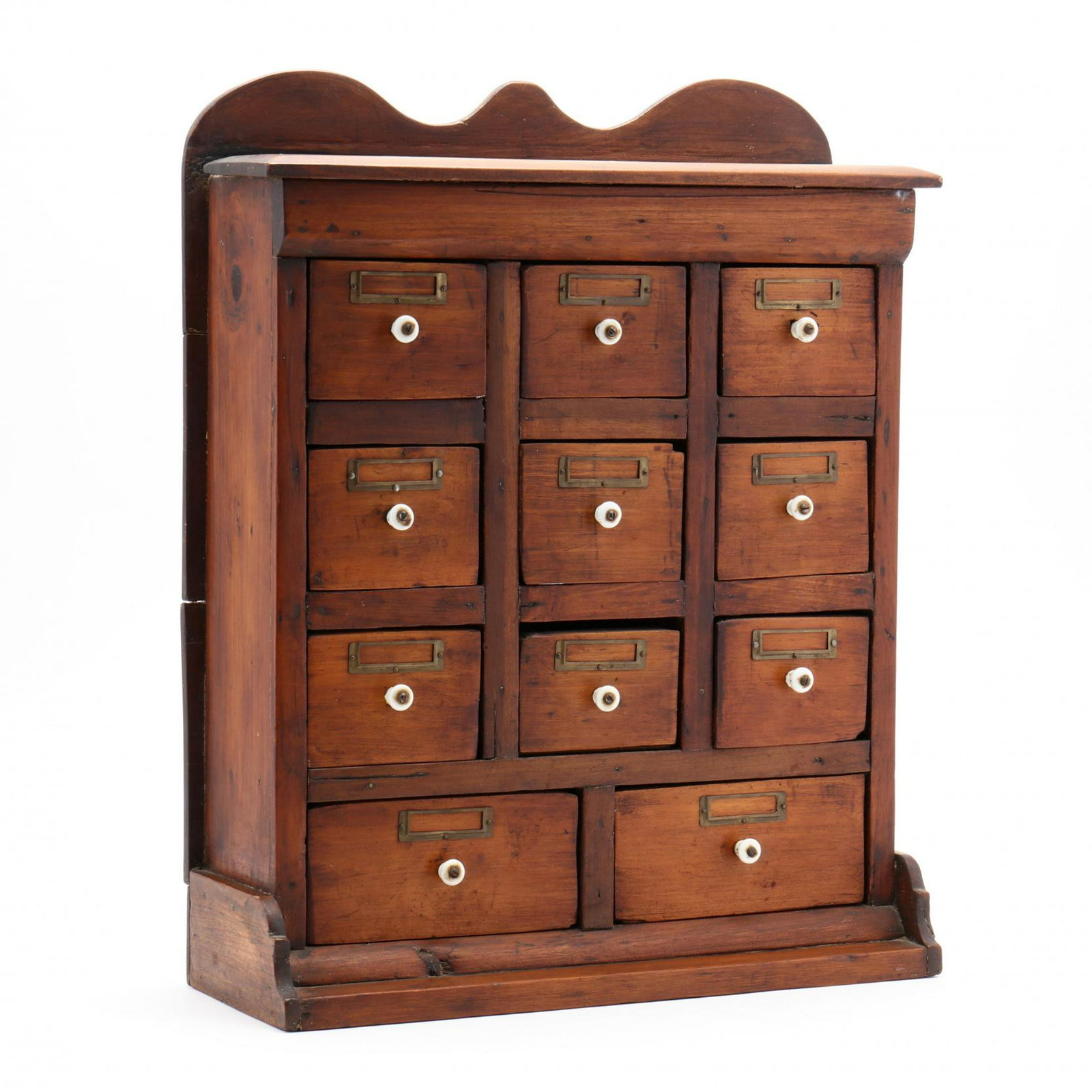 Antique Spice Cabinet: Antique Spice Cabinet late 19th century, pine case with scalloped cornice over eleven drawers constructed from cigar boxes, several with original labels, porcelain pulls with brass label plaques, on a