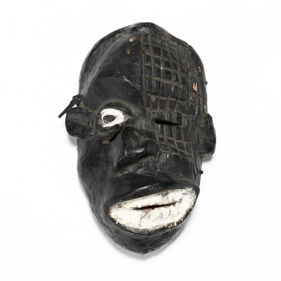 Carved and Painted African Mask With Comic Features: Carved and Painted African Mask With Comic Featureslikely West African, overall black paint with white highlights, the features twisted and misshapen; remnants of strap on the back. 12 x 8 in. Deacces