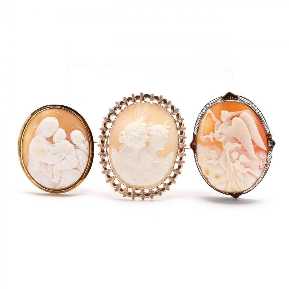 Three Gold Carved Shell Cameo Brooches: Three Gold Carved Shell Cameo Brooches the first depicting the Greek mythological goddesses of dawn and night, Eos and Nyx, within a rose gold open and scalloped surround, testing 14KT (2 5/8 x 2.25 i