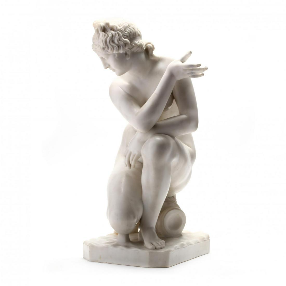 A Carved Marble Statue of the Crouching Venus, 19th: A Carved Marble Statue of the Crouching Venus, 19th Centurycarved and polished white marble, the nude figure with detailed curly hair with ribbon and opened hand kneeling on a wine jug atop a rectangu