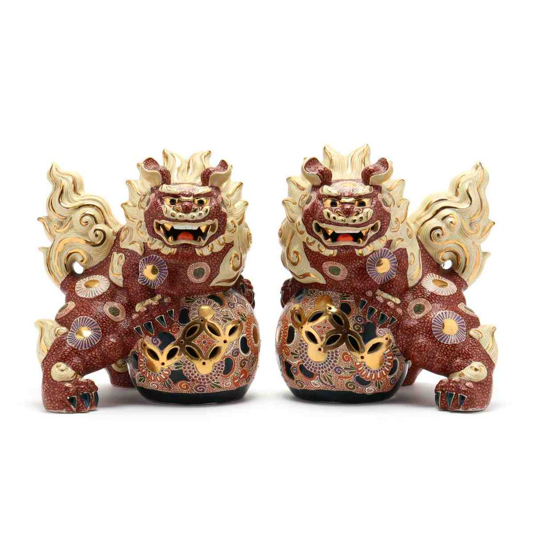 A Pair of Japanese Kutani Satsuma Porcelain Foo Dogs: A Pair of Japanese Kutani Satsuma Porcelain Foo Dogs 19th or 20th century, a very elaborately decorated pair of foo dogs, both holding colorful balls, manes and tails radiate from their bodies in ligh