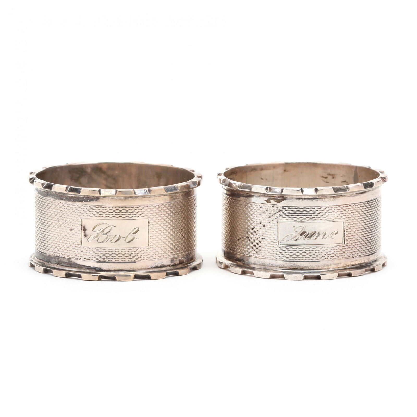 A Pair of Edward VIII Silver Napkin Rings: A Pair of Edward VIII Silver Napkin Ringsmark of John Thompson & Sons, Birmingham (1936), each with engine turned decoration and featuring crenelated edges, one engraved "Bob" and the second engraved