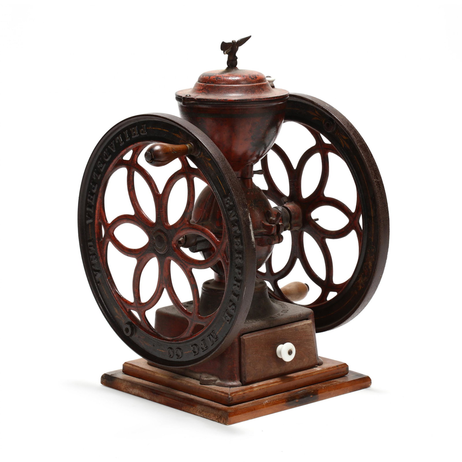 Antique Enterprise Iron Coffee Grinder: Antique Enterprise Iron Coffee Grinder Philadelphia, circa 1893, old red painted surface, gilt metal eagle finial, embossed wheels, with lower walnut drawer. 25 x 20 x 17 in. From the collection of Dr