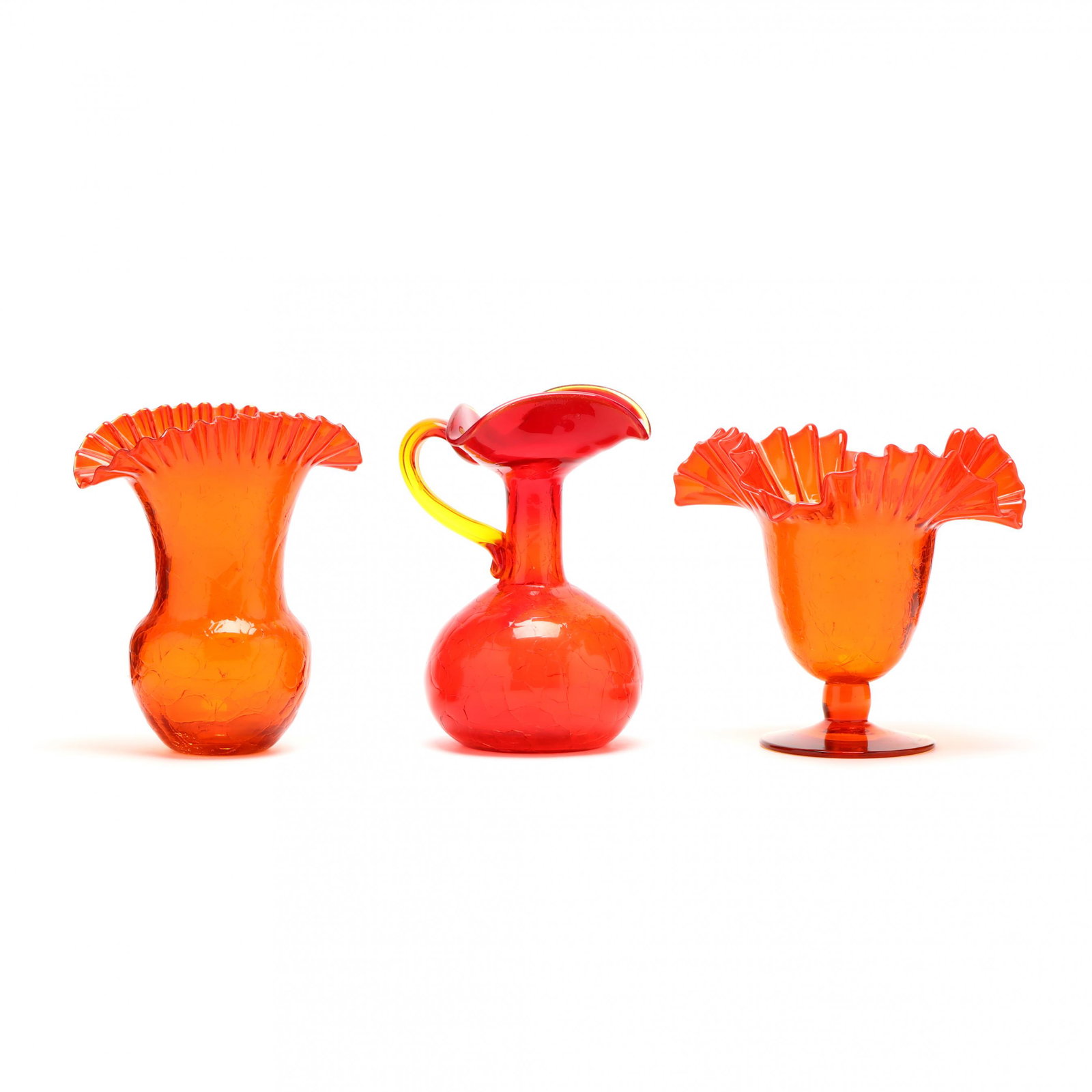 Blenko, Three Pieces of Amberina Crackle Glass: Blenko, Three Pieces of Amberina Crackle GlassWest Virginia, including a tooled rim fan vase, wavy tooled rim footed vase, and an applied handle pitcher, unmarked. Tallest 9 in. Collection of Arlene W