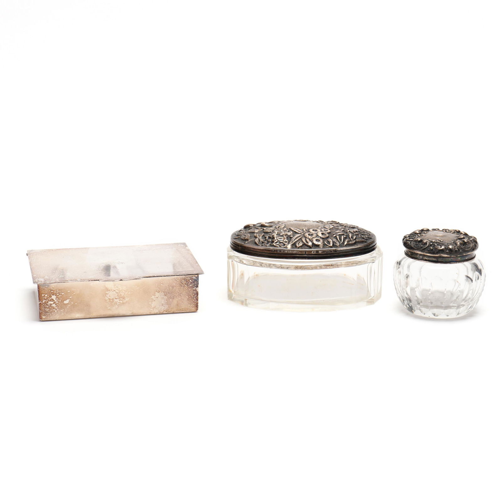 Three Silver Table Accessories: Three Silver Table Accessoriesincluding two sterling lidded glass jars with repousse floral decoration, and a silverplate cigarette box. Longest box 4.5 in. Private Collection, Rome, GA Additional hig