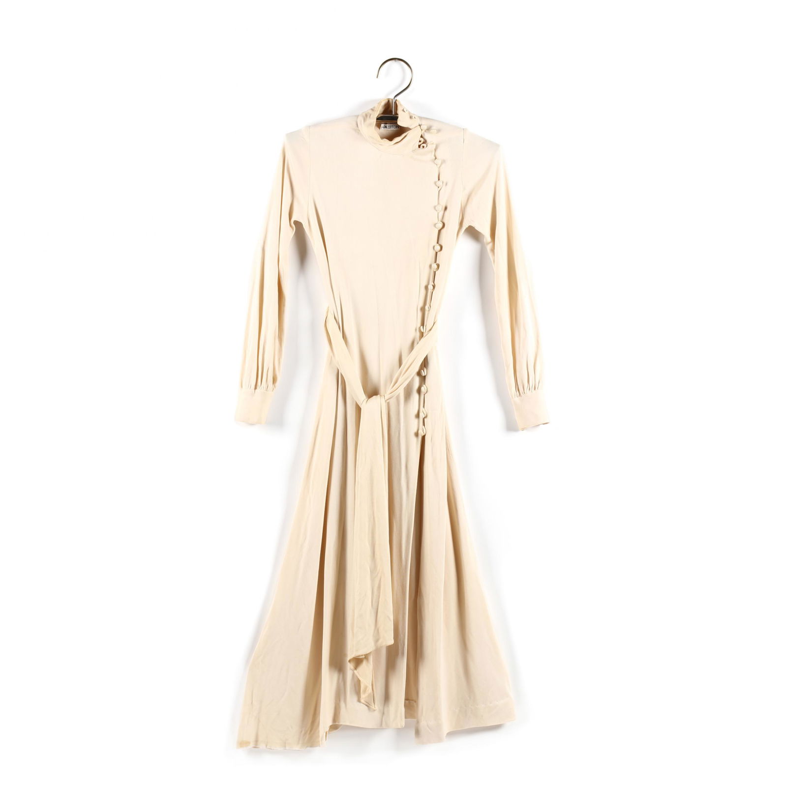 A Cream Maxi Dress, Halston: A Cream Maxi Dress, Halstoncirca 1970s, a hand stitched, cream colored maxi dress made of a stretch poly-jersey fabric with button down side front and with a matching belt / wrap, labeled. Dress: B -