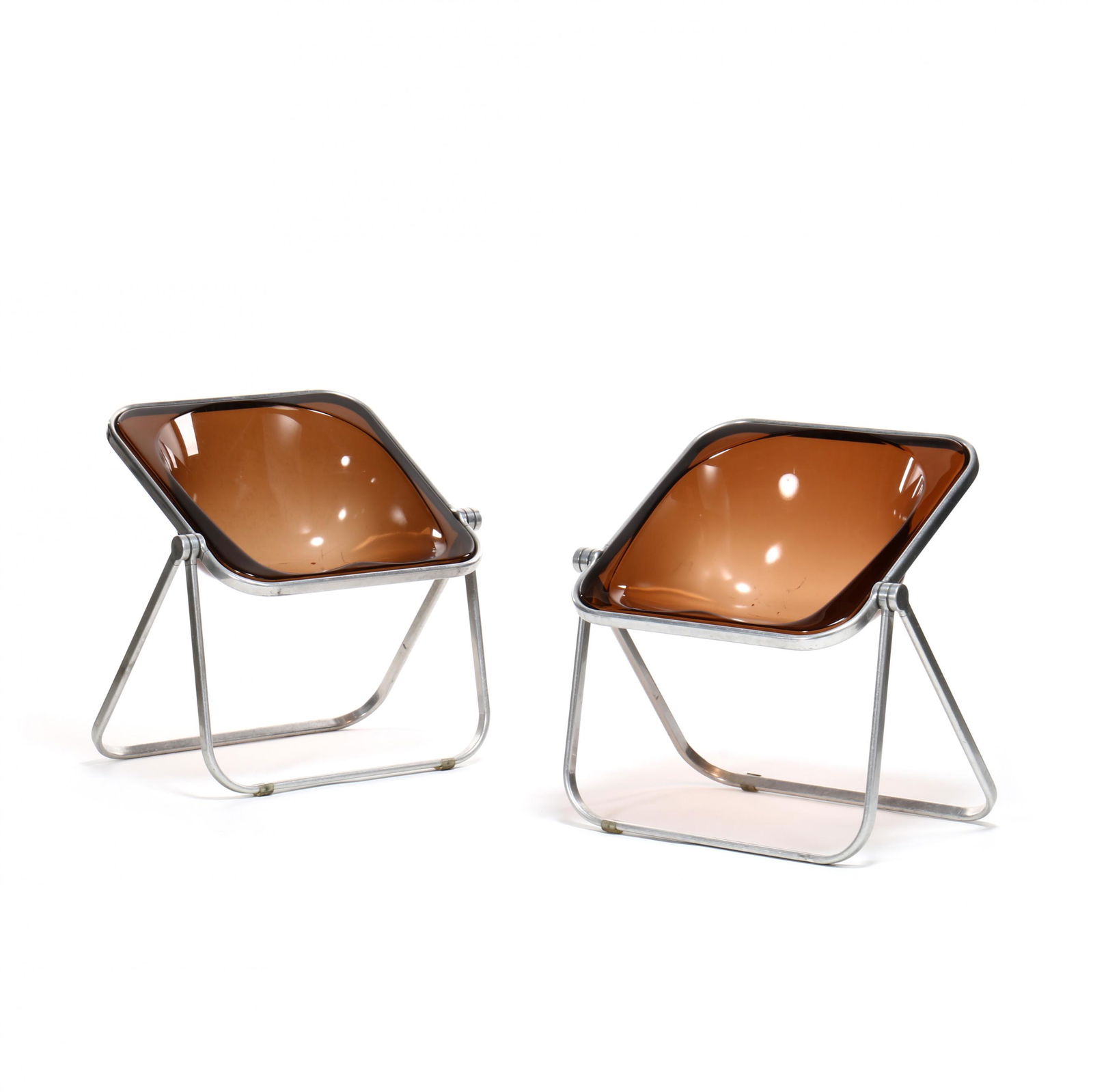 Giancarlo Piretti, Pair of Plona Chairs: Giancarlo Piretti, Pair of Plona Chairs1970s, Italy, for Castelli, molded amber colored lucite shell seat, on hinged aluminum base, labeled. 28 x 27 x 20 in. Known for his lucite folding chairs, the P