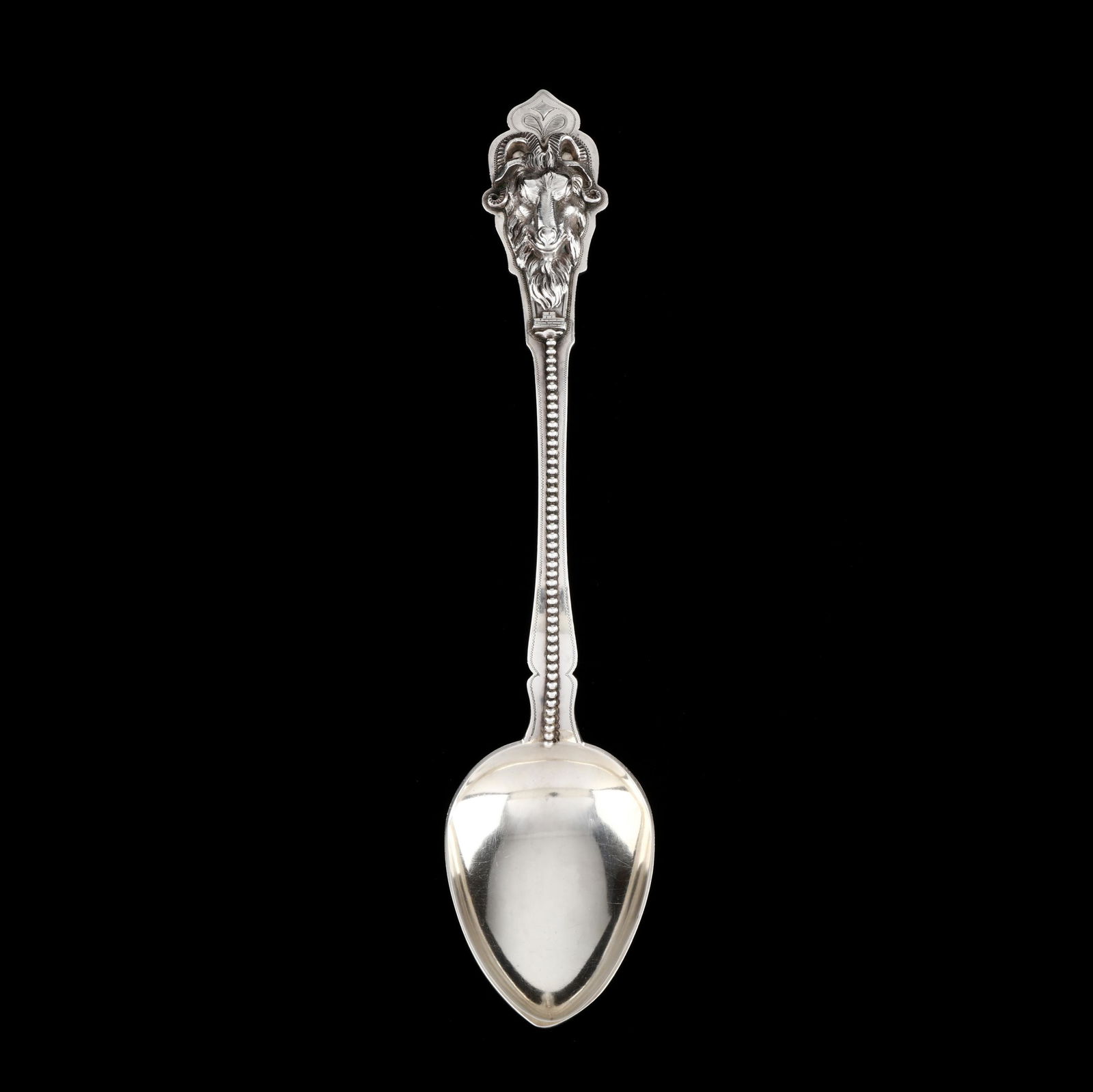 An Unusual Duhme & Co. Coin Silver Serving Spoon: An Unusual Duhme & Co. Coin Silver Serving Spoonfeaturing a ram's head mask in high relief applied to shaped terminus and featuring a lines of beading down handle, no monogram. 12.25 in. 5.75 troy oz.