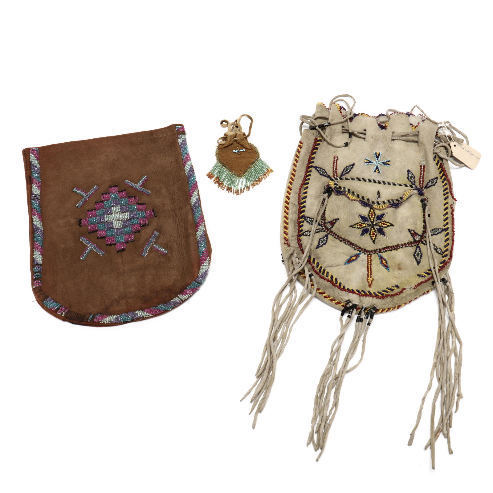 Three Early Navajo Beadwork Bags: Three Early Navajo Beadwork Bags1920s or earlier, the first of deerskin, its face incorporating a small pouch fastened with a hammered silver button, decorated with floral patterns, an eight-pointed s