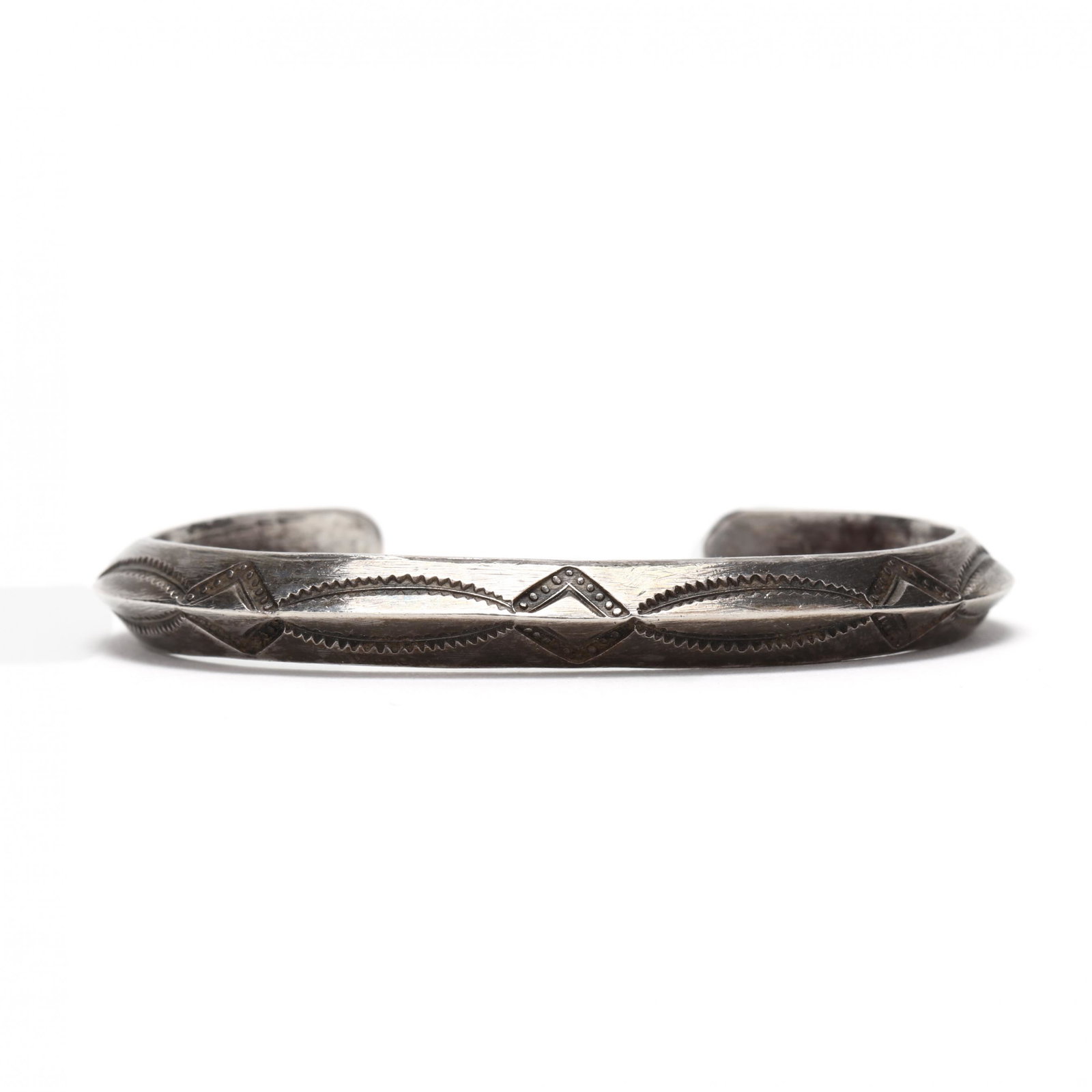 Vintage Navajo Silver Cuff: Vintage Navajo Silver Cuff 1920s or earlier, each plane of the pointed surface has geometric decorations. The interior's width is currently 2.5 in. From the collection of Mrs. Harriet Nottingham, an O