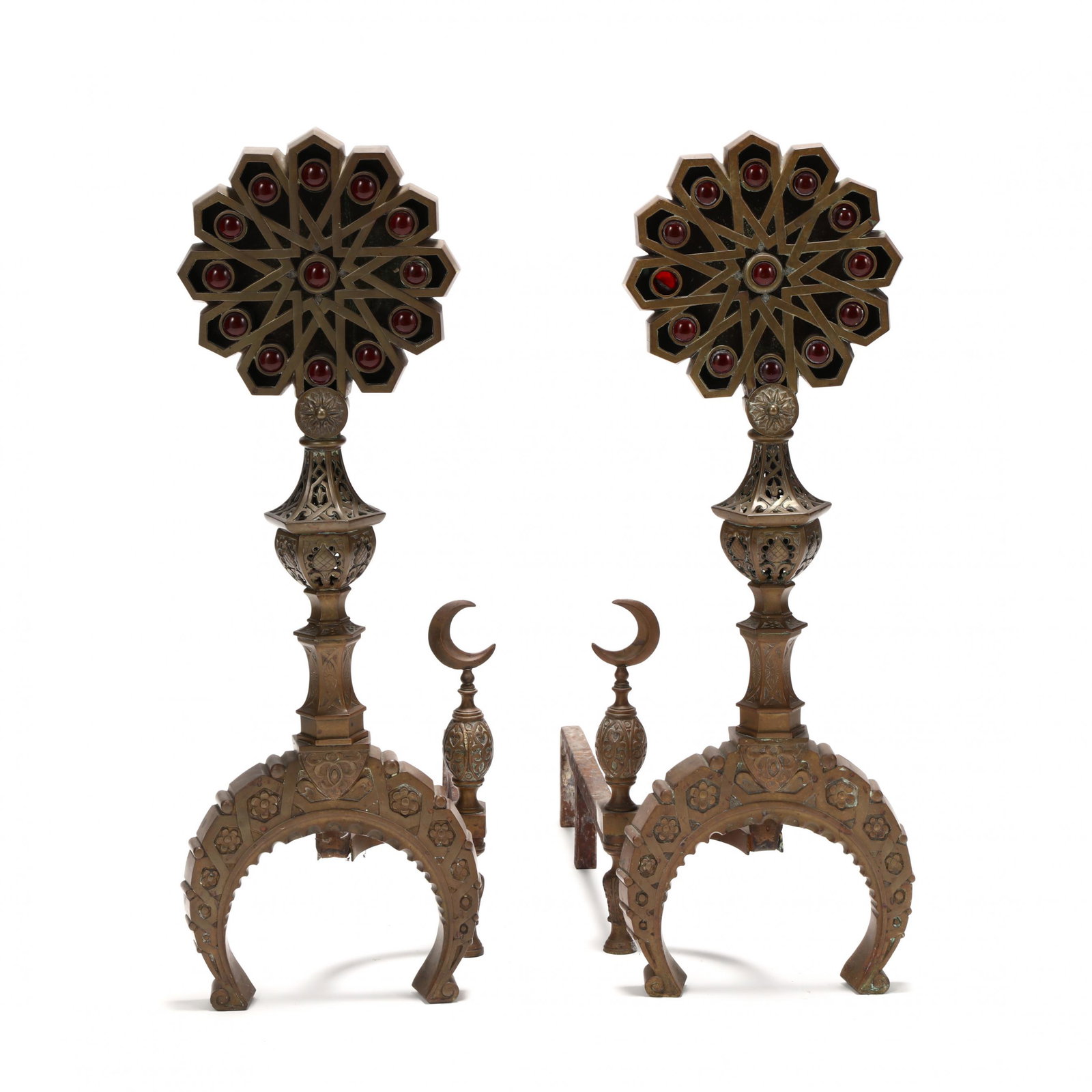 A Pair of Moorish Style Andirons with "Jewels": A Pair of Moorish Style Andirons with "Jewels" late 19th century, unmarked, cast brass with pierced decoration, terminating in large starbursts with inset red glass "jewels," the log supports featurin