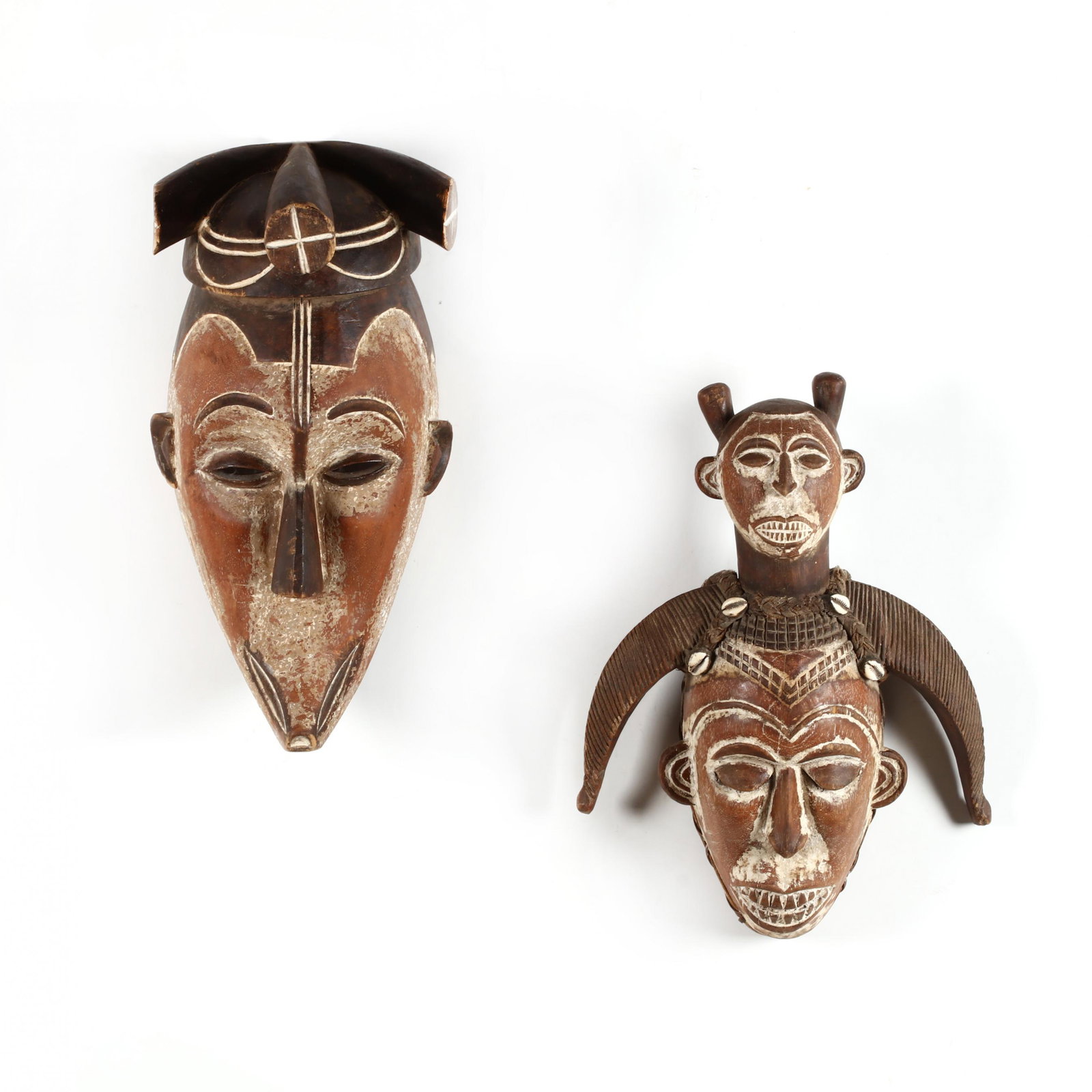 Two Carved African Masks, Ivory Coast: Two Carved African Masks, Coast painted with black, red, kaolin; the first, Senufu, having extend horns wrapped with burlap and cowrie shells (18 in.) (hairlines at chin and left side; burlap unraveli