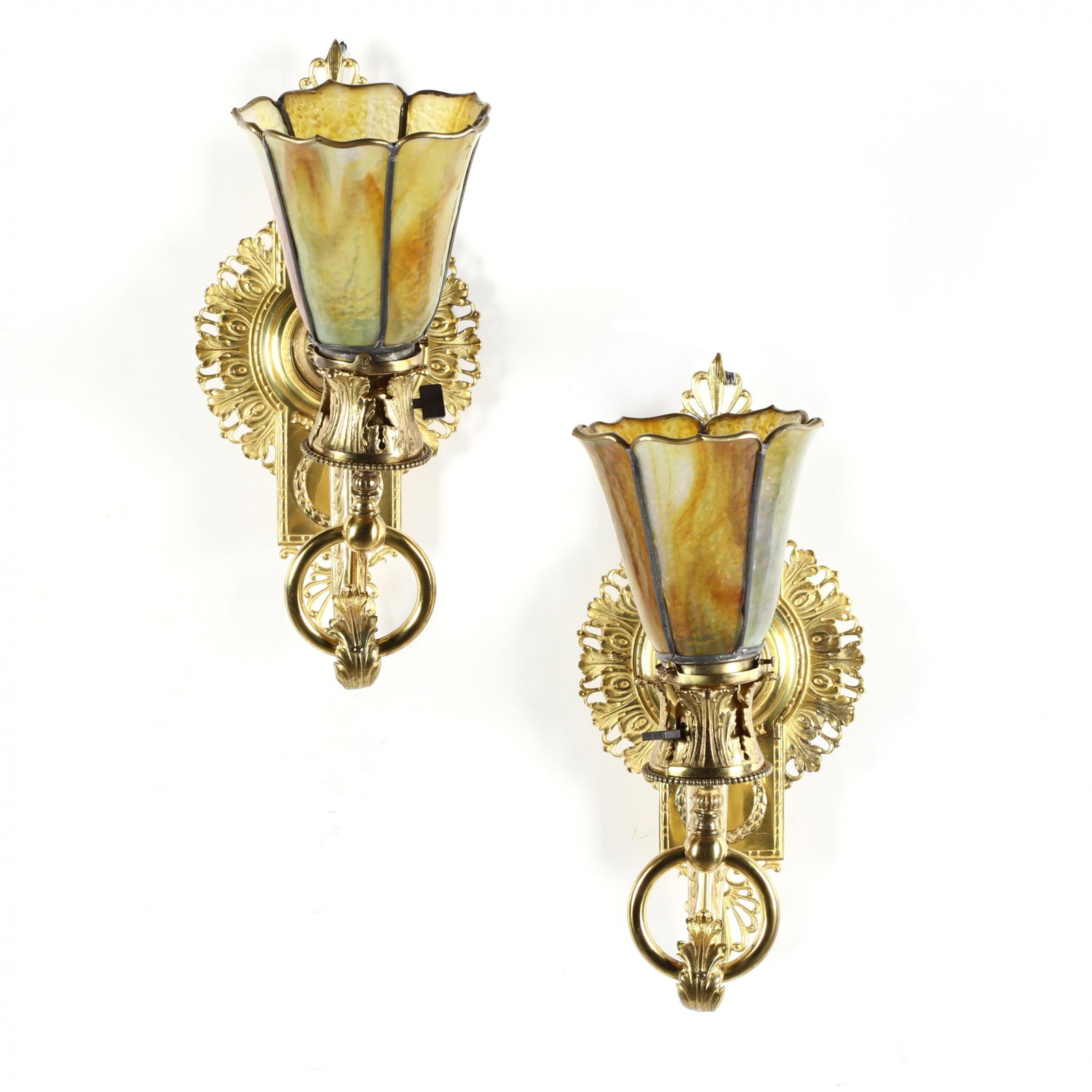 A Pair of Bradley & Hubbard Wall Sconces: A Pair of Bradley & Hubbard Wall Sconces early 20th century, brass, in an ornate French Empire style, with scrolling foliate backplate and arm reaching toward an unfurled sienna and green slag glass l
