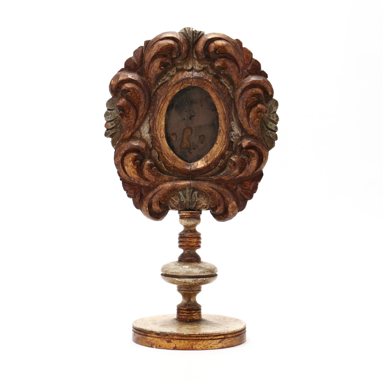Antique Carved Giltwood Reliquary Mirror: Antique Carved Giltwood Reliquary Mirror circa 1900, with carved and gilt oval scrolling foliate frame, supported by a carved baluster and ring-turned standard, on a circular base. HOA 19.5 in. Privat