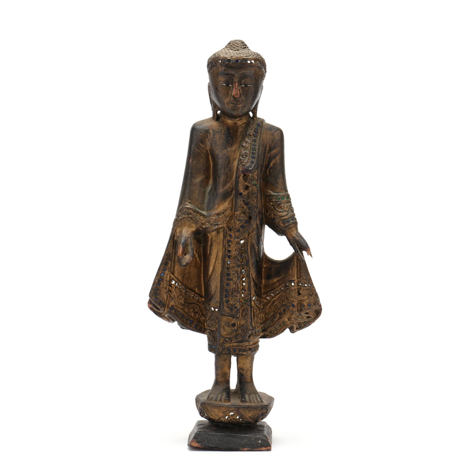 A Carved and Gilt Wood Burmese Buddha: A Carved and Gilt Wood Burmese Buddha 20th century, a standing carved and gilded sculpture of the Buddha in Mandalay style, the robe carved in folds and having inlaid round colored glass along the edg