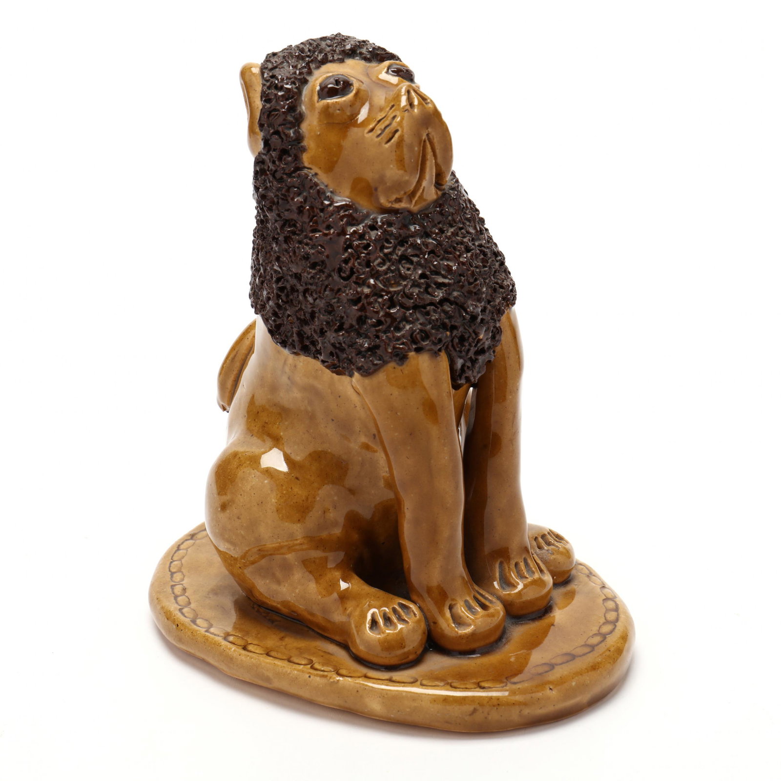 NC Folk Pottery, Billy Ray Hussey, Brown-Eyed Lion: NC Folk Pottery, Billy Ray Hussey, Brown-Eyed Lion Seated on a decorated platform, the clear glazed earthenware lion features brown eyes and mane, inscribed on the underside "BH". 7.5 x 6.5 in. From t