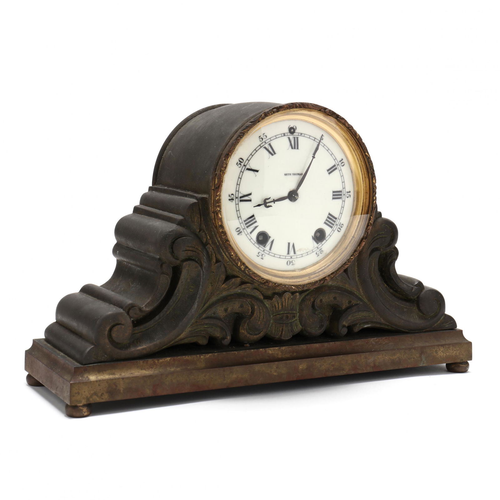 Seth Thomas Mantel Clock: Seth Thomas Mantel Clocktime and strike brass movement, marked porcelain dial with Roman numerals, bronze tone metal construction with scrolled foliate decoration, raised on a pad footed base. 8.5 x 1