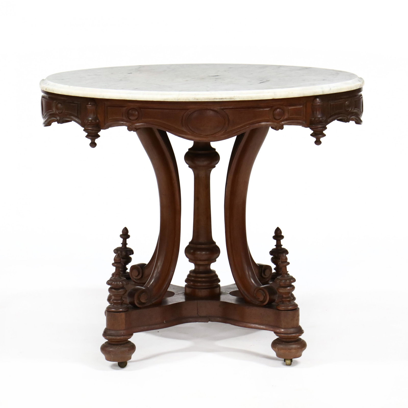 American Renaissance Revival Marble Top Parlor Table: American Renaissance Revival Marble Top Parlor Table 1880s, white oval marble top with molded edge, carved walnut base with central turned standard on four scroll supports with turned feet and casters
