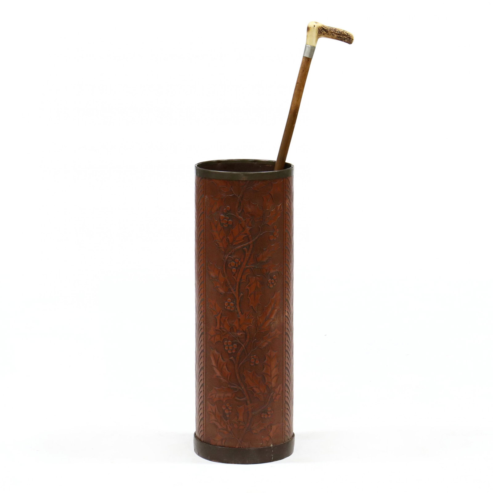 Antique Umbrella Receptacle with Cane: Antique Umbrella Receptacle with Cane early 20th century pressed board receptacle in a holly pattern with brass trim together with an antler handled cane. Receptacle 23.75 x 8 in. diameter; cane 35.5 