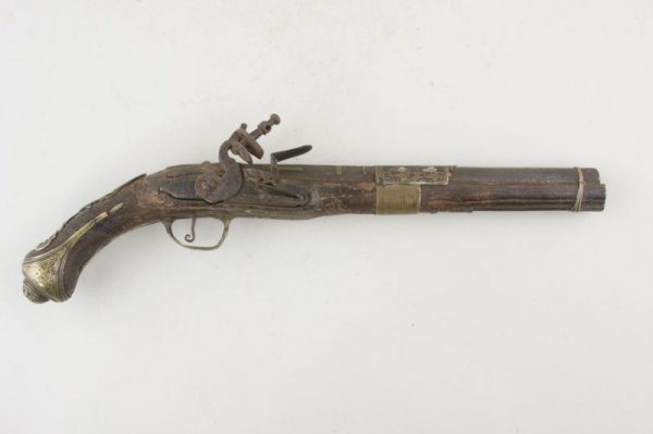 European Flintlock Pistol,: likely Spanish or Italian, 18th c., 10.25" barrel with 11/16" bore, 16.5" LOA, decoratively carved wooden stock, ornate brass furniture, iron barrel with brass inlays. Non-functioning, age cracks, shr