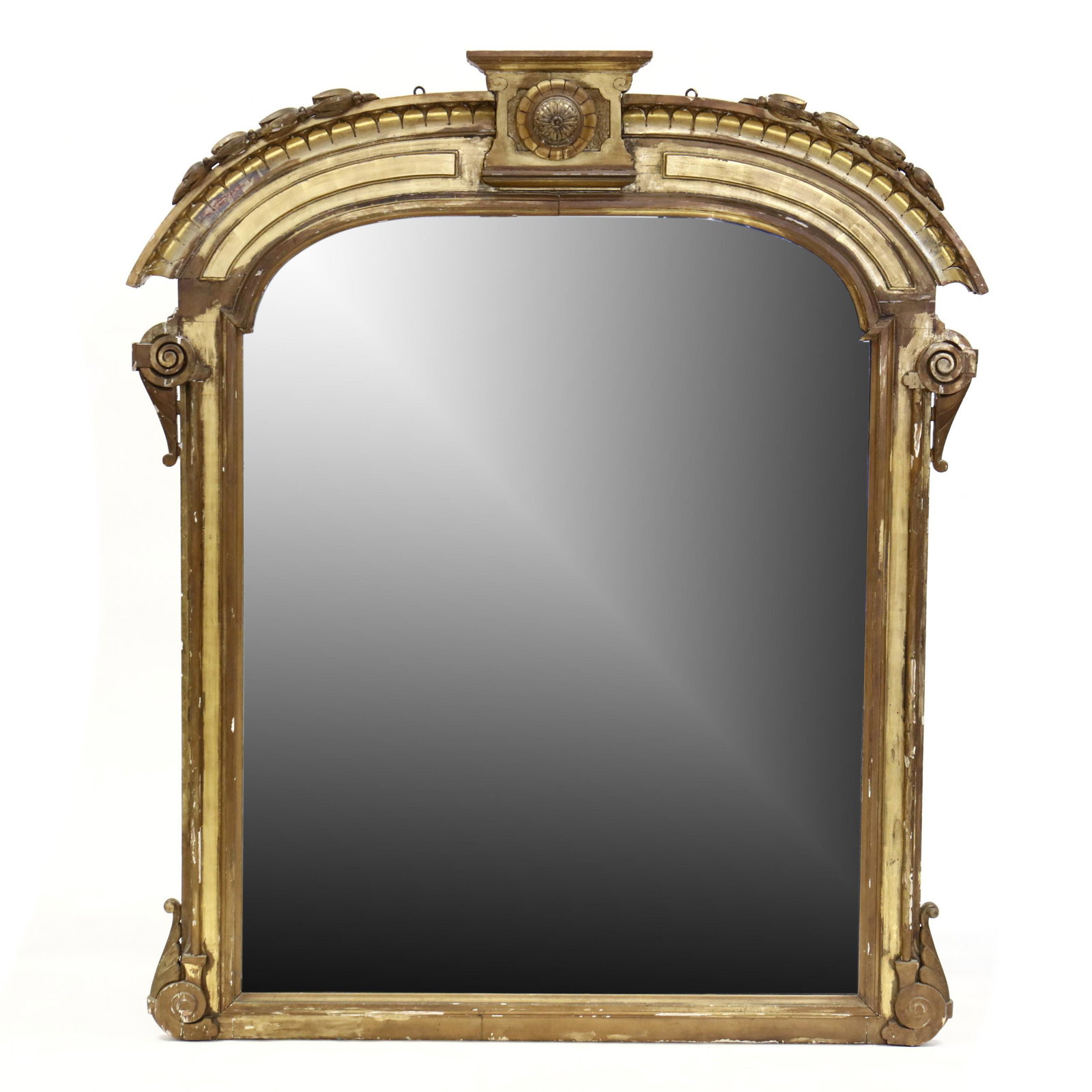 A Large Antique Carved and Gilt Over-Mantel Mirror: A Large Antique Carved and Gilt Over-Mantel Mirror 19th century, wood and gesso frame with arched molded pediment featuring central relief carved rosette and graduated bellflowers, shaped arched and m